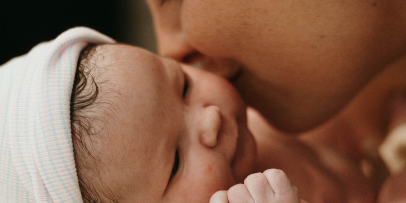 A mother nuzzles her newborn baby and smiles